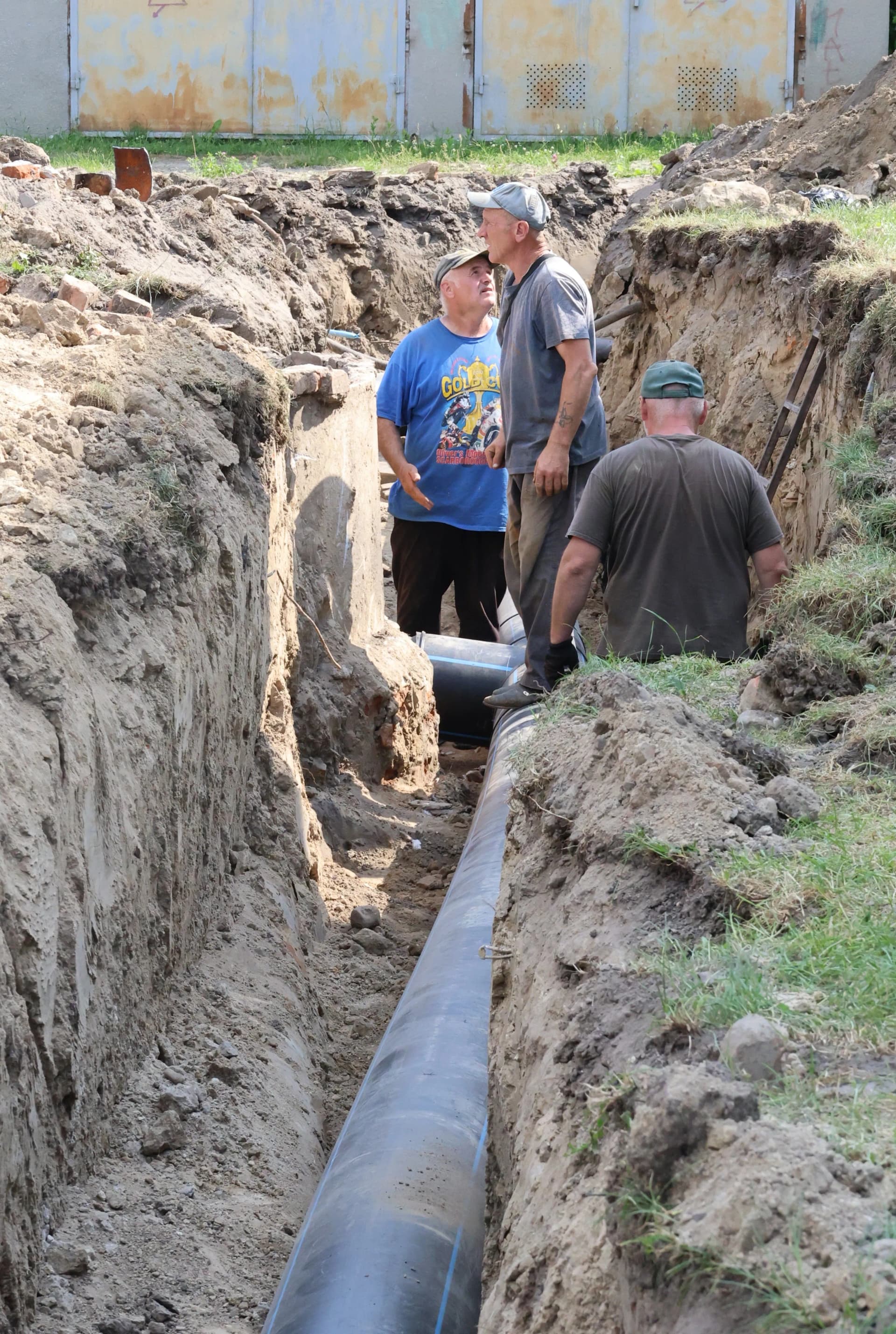 працівники КП "Водоканал" працюють над укладанням нової водопровідної труби