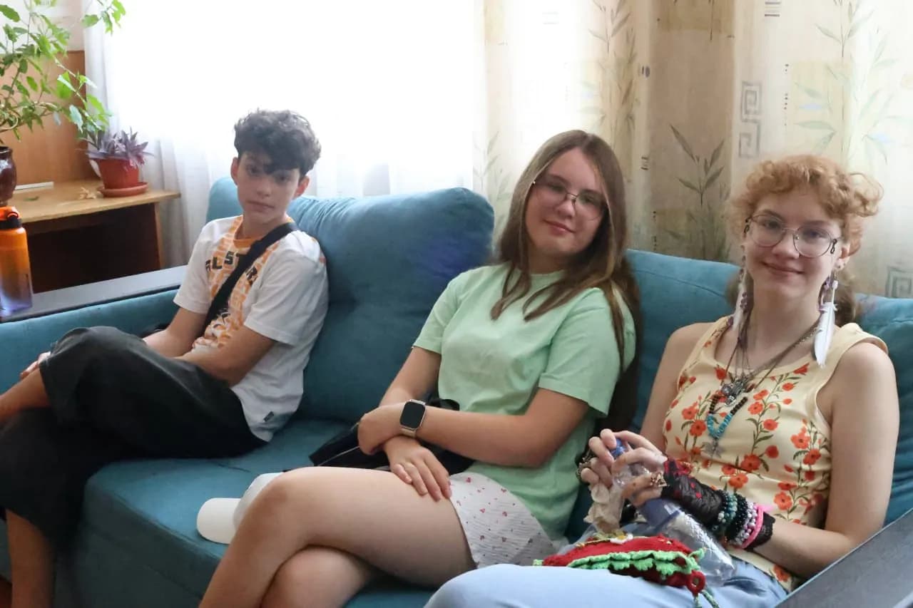 двоє дівчат та хлопець сидять на дивані у класі