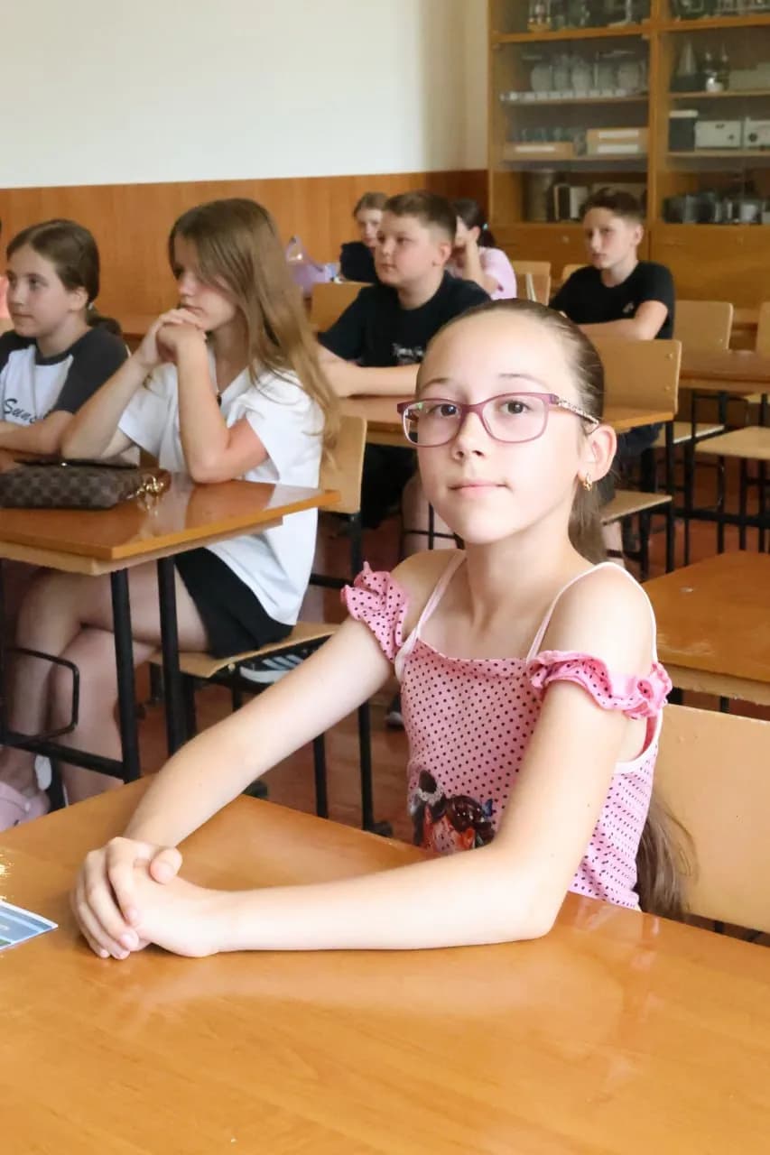 Дівчинка в окулярах сидить за партою