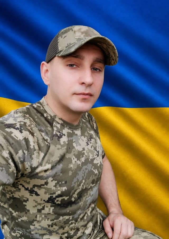 на фото загиблий Герой Шкудор Володимир Васильович на фоні жовто-блакитного прапору