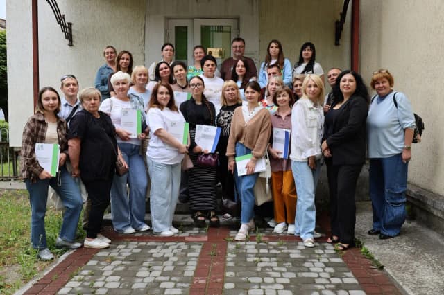 Люди стоять перед будівлею Агенції справедливої трансформації