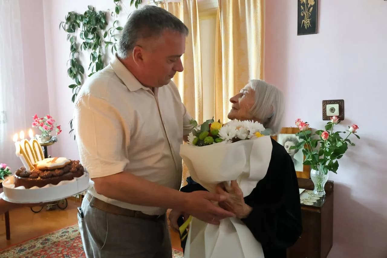 Заступник міського голови вручає квіти ювілярці