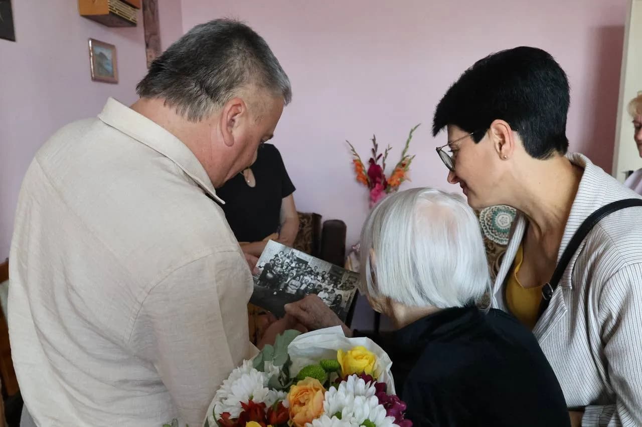 Гості з ювіляркою розгяладають її старі світлини