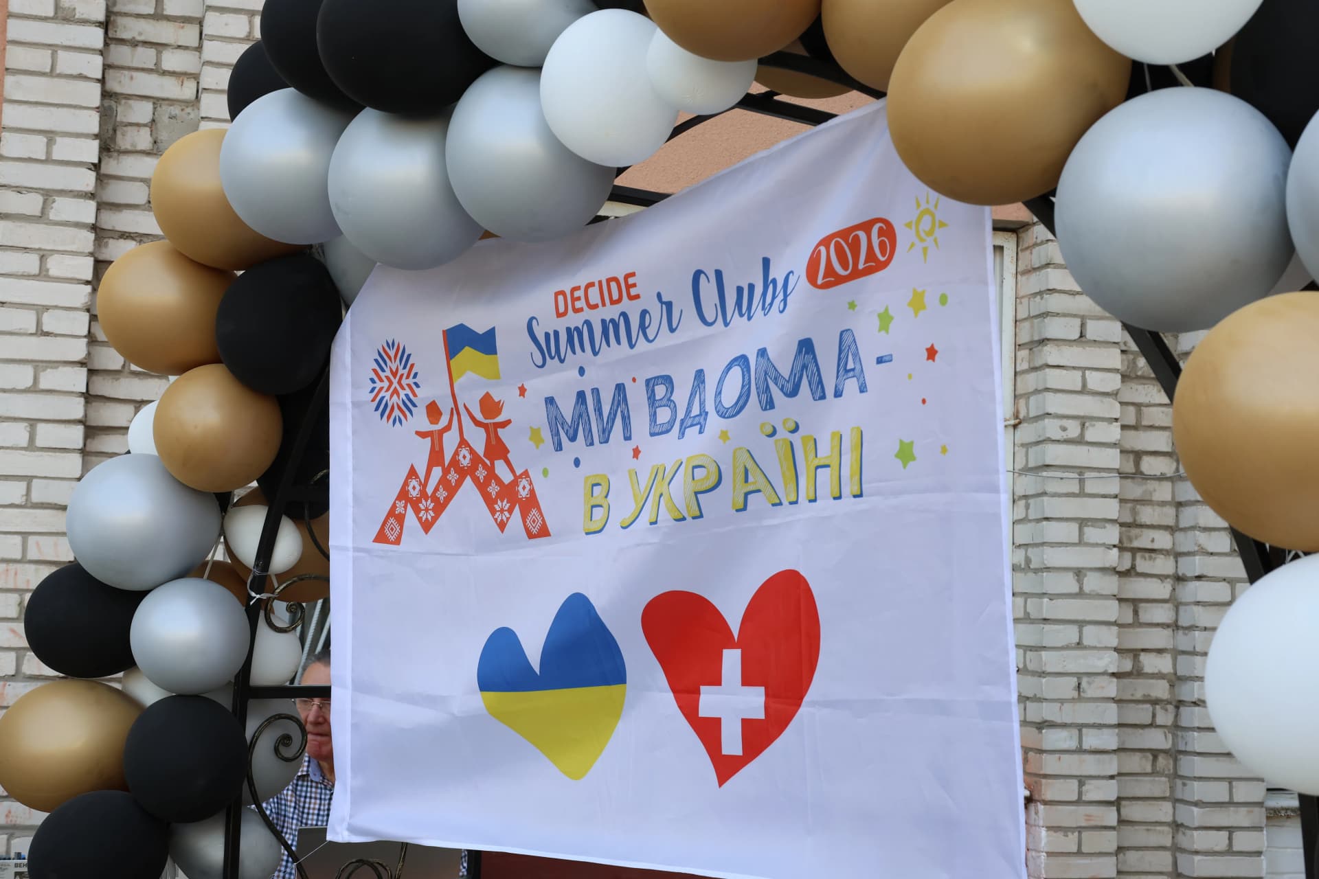 плакат з повітряними кульками, на якому напис "Summer club DECIDE. Ми вдома - ми в Україні"