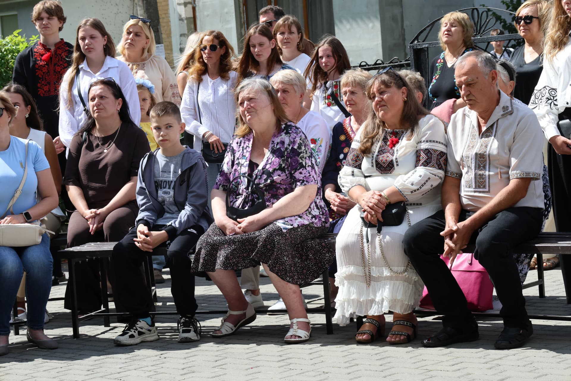 люди сидять на лавці на подвір’ї школи