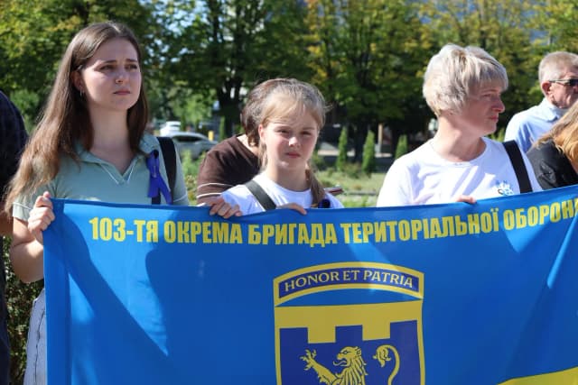 дві жінки і дівчинка з прапором 103 ТРО