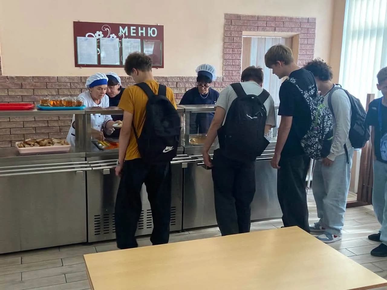школярі в їдальні стоять в черзі за порцією