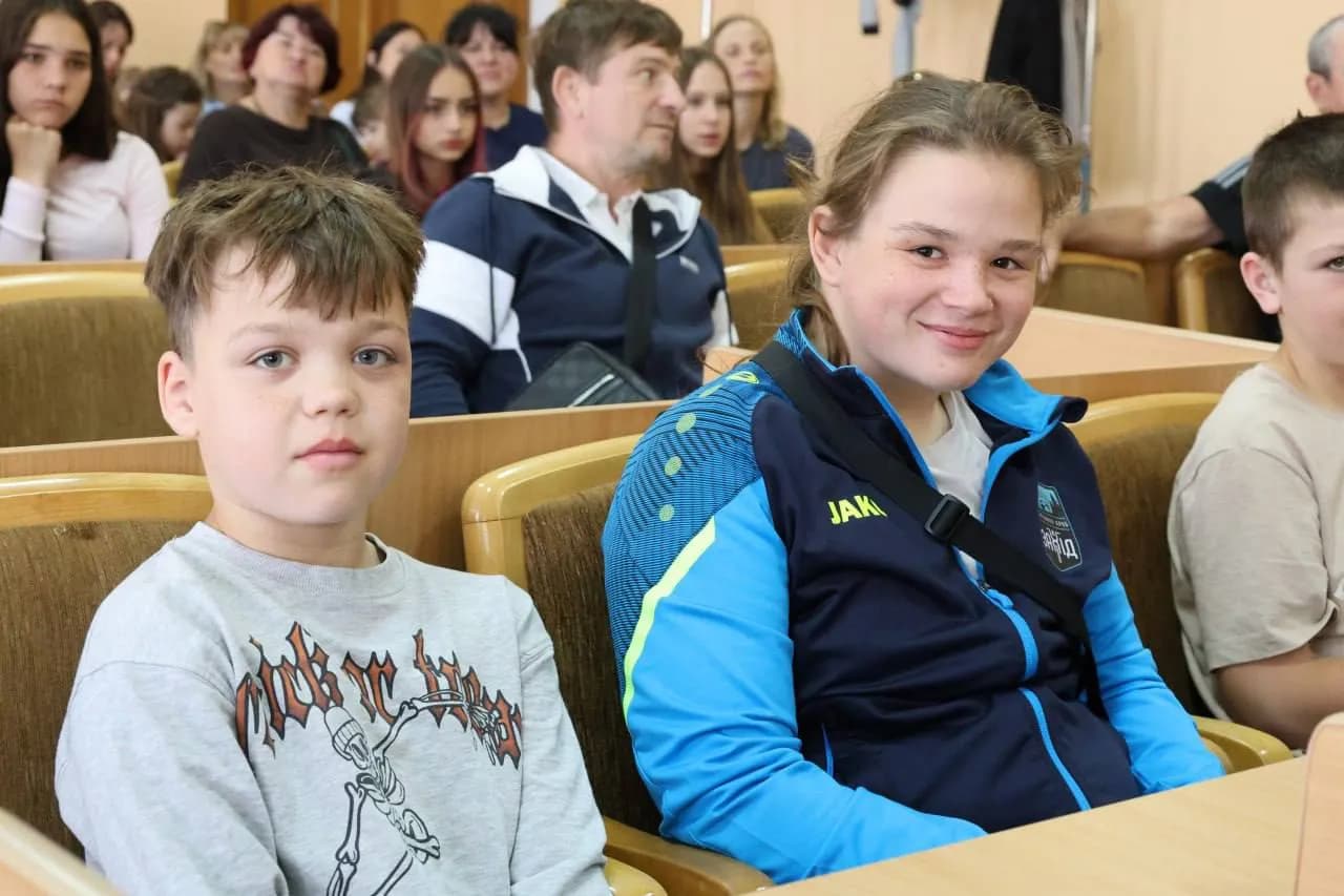 молодь сидить на стільцях та слухає хокеїста