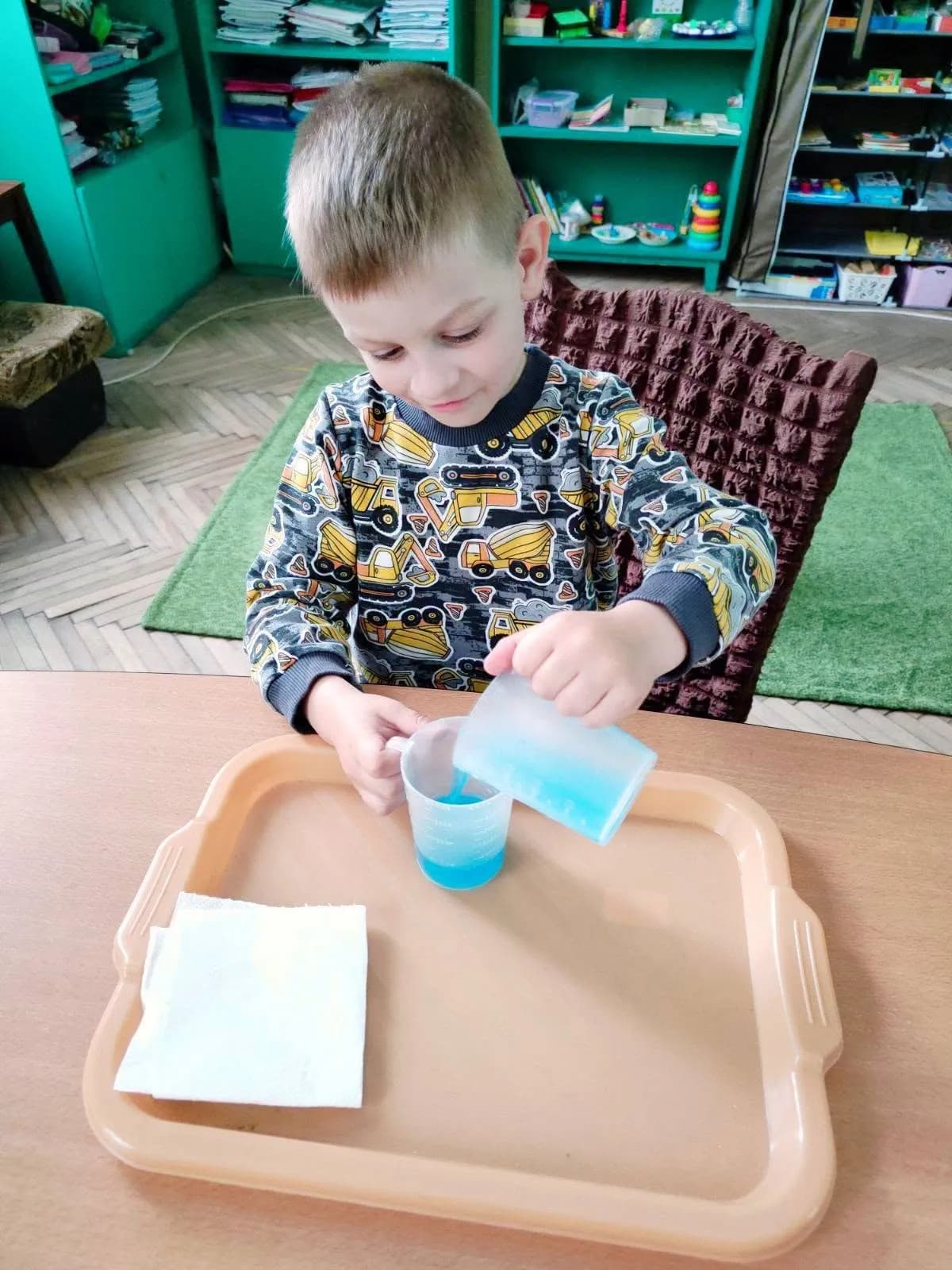 хлопчик в стакан наливає воду синього кольору