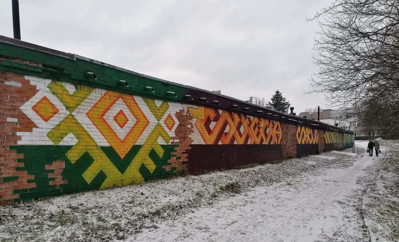 Паркан розмальований геометричними фігурами (ромбами) у жовто-зелених кольорах