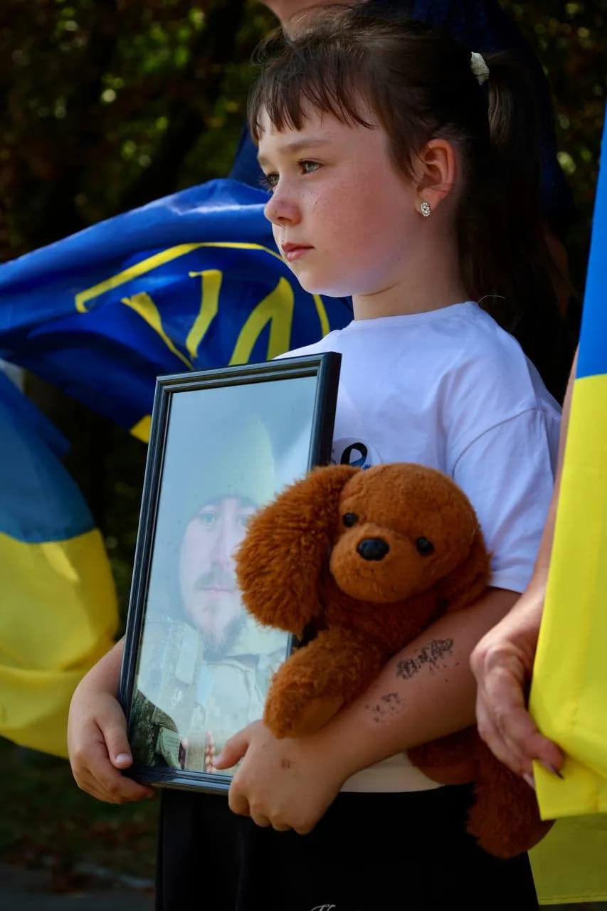 Дівчинка тримає іграшку та портрет зниклого безвісти тата