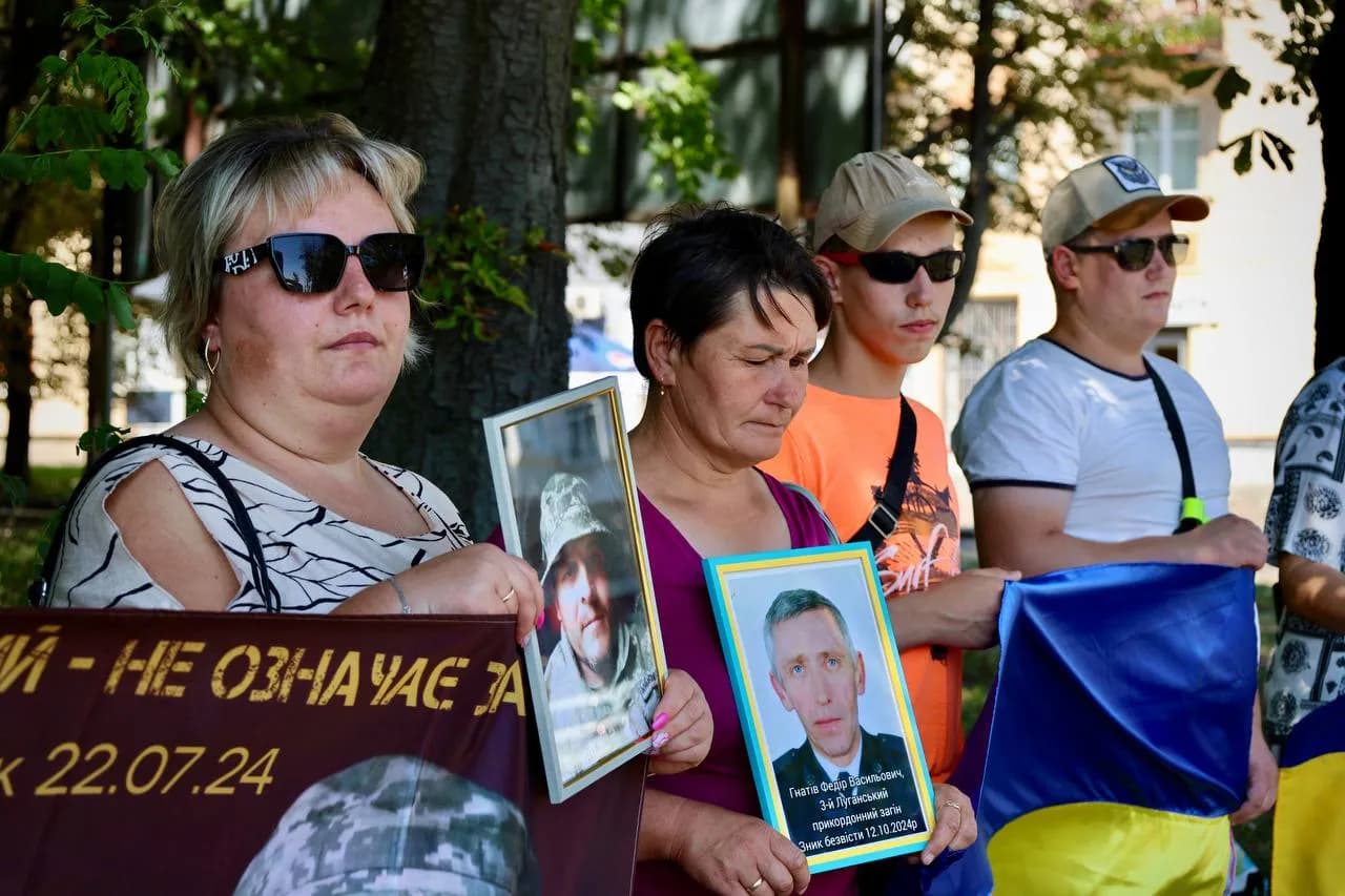 Люди з прапорами та портретами зниклих безвісти родичів