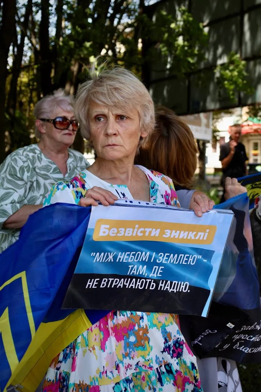 Жінка з прапором та плакатом, де пише "Безвісти зниклі «Між небом і землею — там, де не втрачають надію»! "