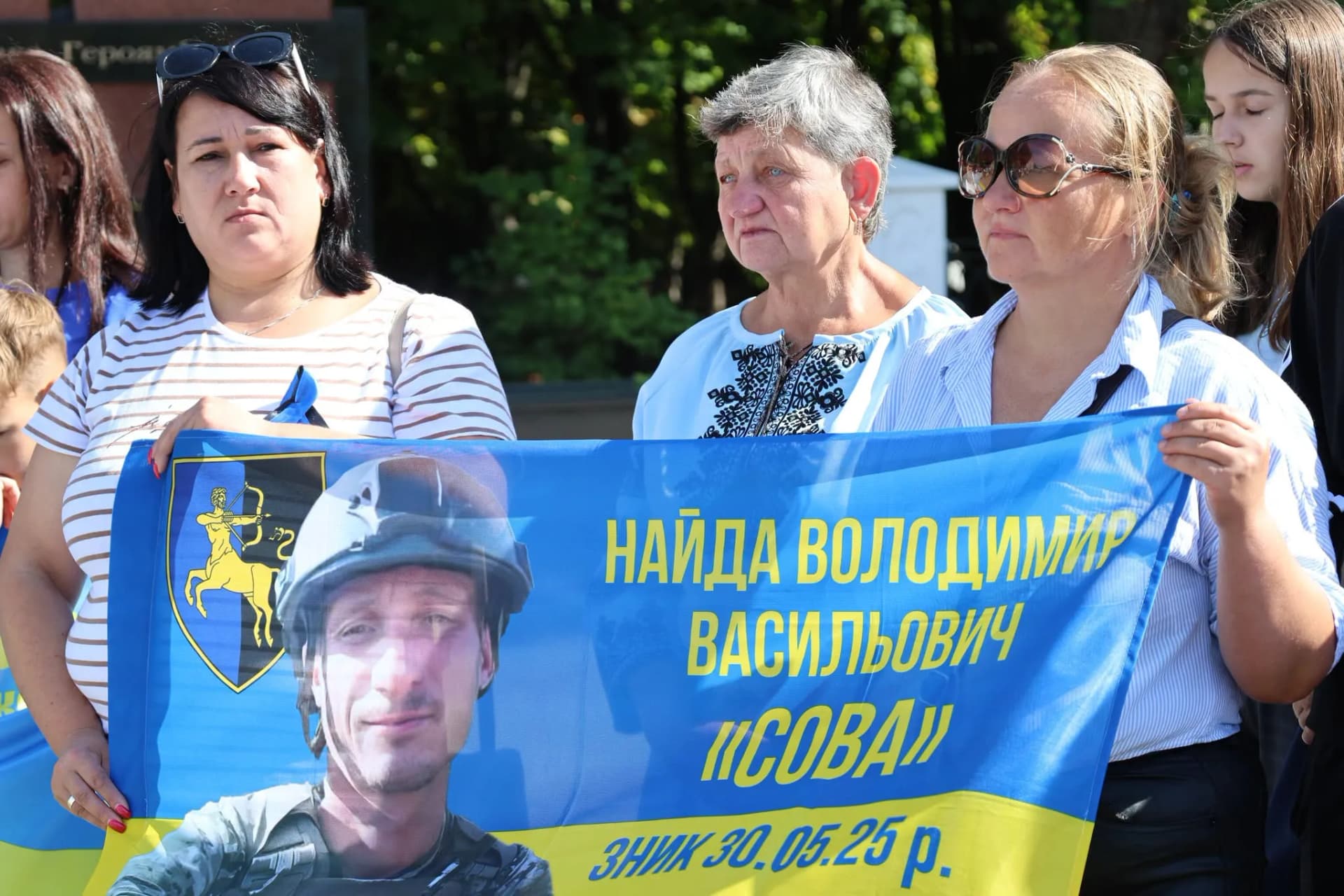 жінки з прапором, на якому портрет військового