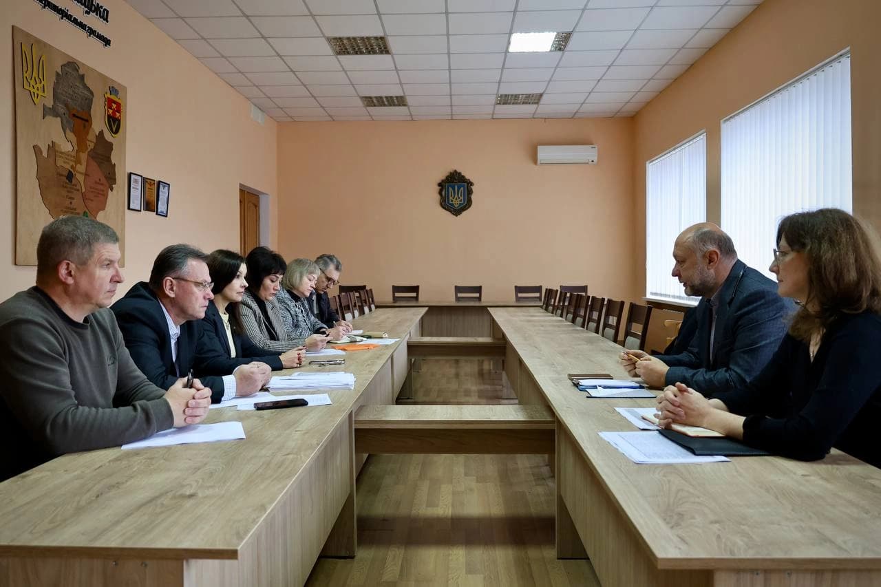 Учасники зустрічі сидять за столами один напроти одного