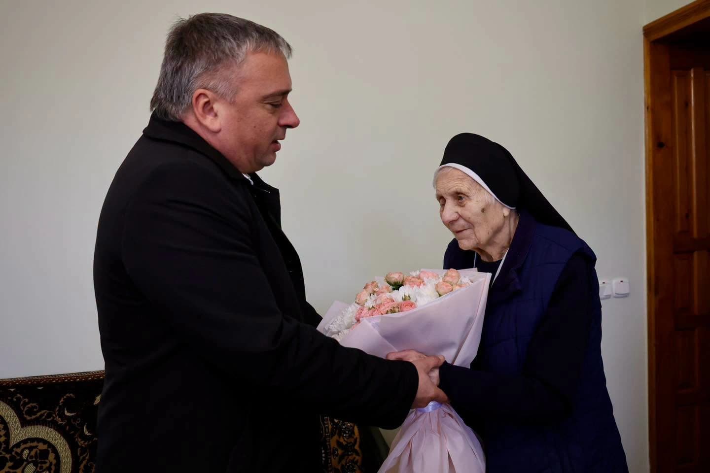 заступник міського голови Володимир Коваль вітає сестру Дарію Градюк зі 101-річчям